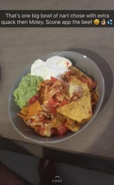 a bowl filled with nachos and guacamole on top of a table