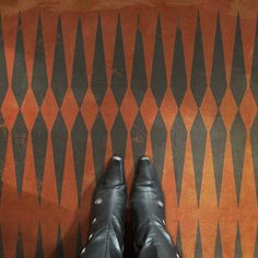 a pair of black shoes sitting on top of a floor next to an orange and black wall