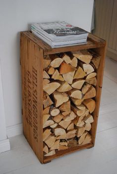 a stack of firewood in a wooden crate on the floor next to a wall