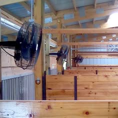 the inside of a building with wooden benches and fans hanging from the ceiling above them