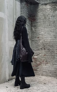 a woman with long black hair is carrying a brown bag