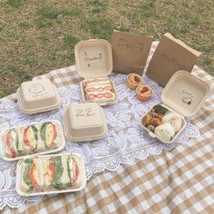 a picnic table with sandwiches and other food items on it, including an open lunch box