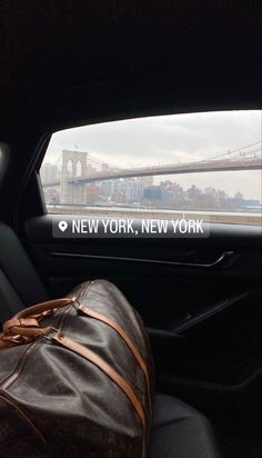 the back seat of a car with luggage in front of it and a view of brooklyn bridge