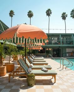 lounge chairs and an umbrella on the side of a swimming pool