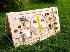 a wooden board with various electrical devices attached to it on the grass in front of some bushes