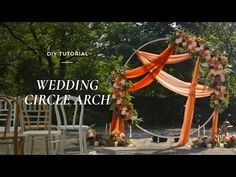 an outdoor wedding circle arch decorated with flowers and orange draping for the ceremony