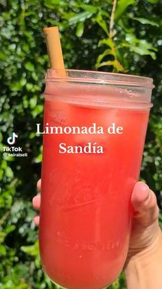 someone holding up a drink with a straw in it's mouth and the words lemonade de sandia above it