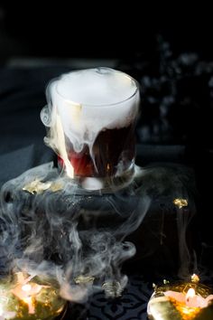 a cup with some liquid in it sitting on top of a table next to candles