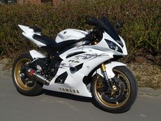 a white and black motorcycle parked on the side of a road next to some bushes