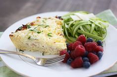 a white plate topped with food next to a fork and salad on top of a table