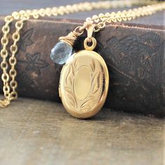 "A lovely gold filled locket graces this necklace. The vintage piece has classic swirled etched on the front; the back is plain. The 12k gold filled pendant is hallmarked on the inside which has two frames to place your beloved photos beneath. The locket has been set on a new 14k gold filled chain and paired with a wire wrapped aquamarine briolette (March birthstone). The necklace is finished with a lobster clasp. Locket 26x17mm Necklace 18\" (45cm) ✦All of our vintage lockets ship with complime Heirloom Oval Pendant Locket Necklace For Anniversary, Vintage Gold Locket Necklace With Oval Link, Vintage Gold Oval Link Locket Necklace, Heirloom Style Oval Pendant Locket Necklace With Vintage Charm, Elegant Oval Pendant Locket Necklace From Vintage Collection, Elegant Oval Pendant Locket Necklace For Vintage Collection, Elegant Birthstone Medallion Locket Necklace, Classic Antique Gold Locket Necklace With Vintage Charm, Gold Locket Necklace With Birthstone For Keepsake