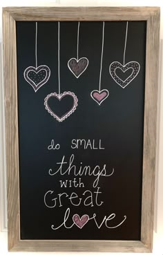 a chalkboard with hearts hanging from it and the words do small things with great love