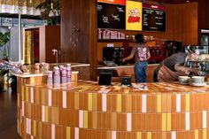 two men working behind the counter at a coffee shop with colorful tiles on the walls