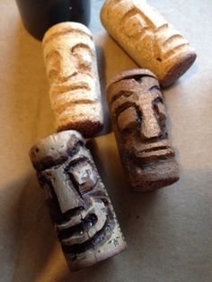 three wooden carved faces sitting next to a black cup