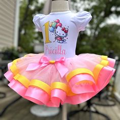 Customizable Kitty Birthday Outfit, Kitty Birthday Outfit, Personalized Hello Birthday Shirt, Cat Tutu Outfit, 1st 2nd 3rd 4th 5th Birthday This adorable Kitty Outfit features a pink tutu with bubble gum pink satin ribbon layered with a yellow glitter ribbon. The shirt has a cute Birthday Kitty design along side with your own personalized age number and name. This design is sublimated meaning the design is heat pressed into the shirt for long lasting quality and durability. The number and name is customizable, if you would like to edit the colors please contact me with your details. PROCESSING TIME IS CURRENTLY 1 WEEK FROM THE DAY YOU PURCHASE. Processing time does not include shipping which is an additional 3-5 business days WITH FREE SHIPPING. If you need your order sooner I have a rush Hello Kitty Birthday Outfit, 1st Birthday Tutu, Birthday Tutu Outfit, Yellow Glitter, Pink Tutu, Glitter Ribbon, Tutu Outfits, Hello Kitty Birthday, Birthday Tutu