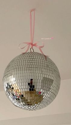 a disco ball hanging from the ceiling with a pink ribbon around it's edge