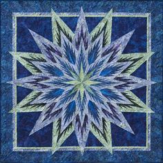 a blue and green quilt with a star design on the center, as well as an intricate