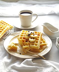 a plate topped with waffles next to a cup of coffee