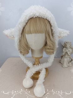 a wig with white fur on top of a wooden table next to an angel figurine