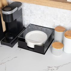 a coffee maker sitting on top of a counter next to two cups and a cup holder