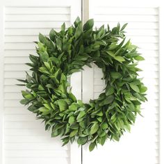 a green wreath hanging on the side of a white door