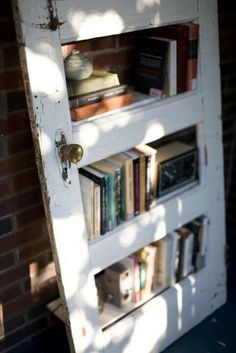 a book shelf with several books on it and the door is open to let in light