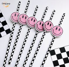 four black and white checkered paper straws with pink smiley faces on each one