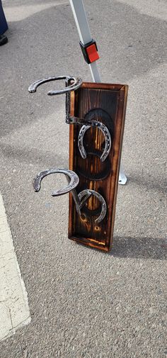 a wooden box with metal handles and horseshoes in it on the ground next to a street sign