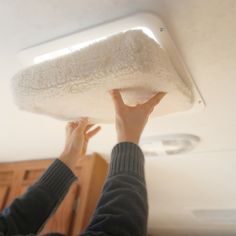 a person holding up a white object in the air above their head and hand on top of it