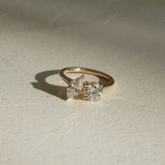 three stone diamond ring sitting on top of a white surface with light shining through it