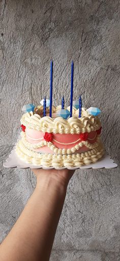 a hand holding a cake with candles on it