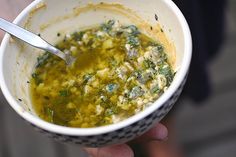 a person holding a bowl of food with a spoon in it