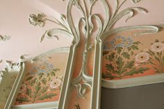 an ornately decorated mirror in the corner of a room with pink walls and ceiling