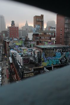 the city skyline is covered in graffiti as seen from an elevated walkway over looking other buildings