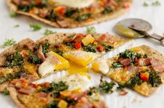 two flatbread pizzas with eggs, bacon and spinach on them next to a spoon