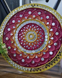 an intricately designed plate sitting on top of a wooden table next to a potted plant