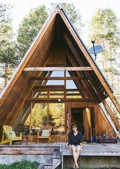 a woman sitting on the steps in front of a wooden cabin with stairs leading up to it