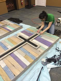 a woman is working on some kind of wooden cross that she made out of pallet wood