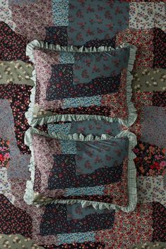 four pillows are stacked on top of each other in the middle of a quilted bedspread