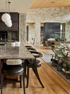 a kitchen and dining room with wood flooring, stone walls and an island in the middle