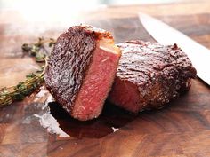 a piece of meat sitting on top of a wooden cutting board next to a knife