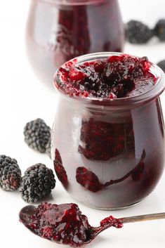 two jars filled with raspberry jam and blackberries next to eachother