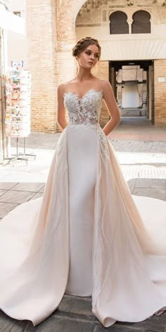 a woman standing in front of a building wearing a wedding dress