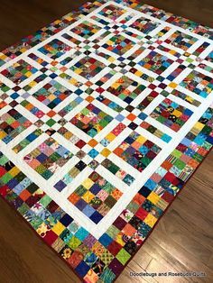 a quilt is laying on the floor with it's squares in different colors and sizes