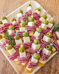 an appetizer platter with olives, cheese and meat on skewers