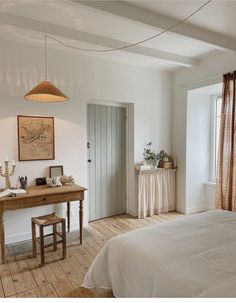 a bedroom with white walls and wooden floors