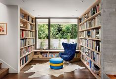 a room filled with lots of books and furniture next to a window covered in trees