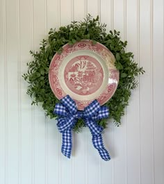 a red and white plate sitting on top of a green wreath next to a wall