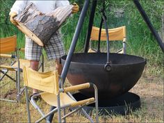 a man standing next to a large pot on top of a metal pan with chairs around it