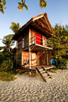 a house on the beach with stairs leading up to it's roof and windows